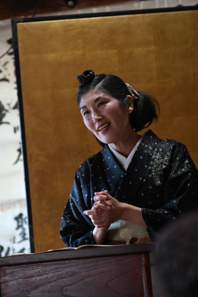 Kanda Masami performing kodan in a dark blue kimono
